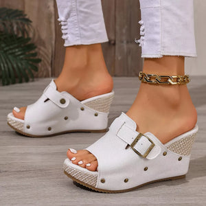 White wedge sandals with decorative accents and buckle detail.