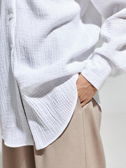 White textured cotton overshirt with relaxed fit and button front, shown with hand in pocket.