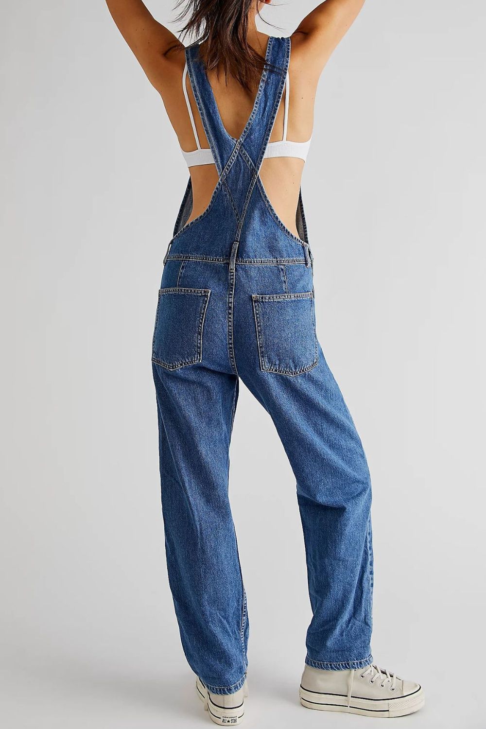 Relaxed fit denim overalls in medium wash with crisscross straps and back pockets.