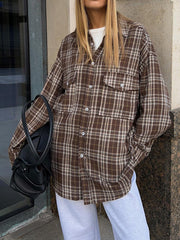 Brown plaid shacket with button-up front and chest pockets, worn open over a white tee.