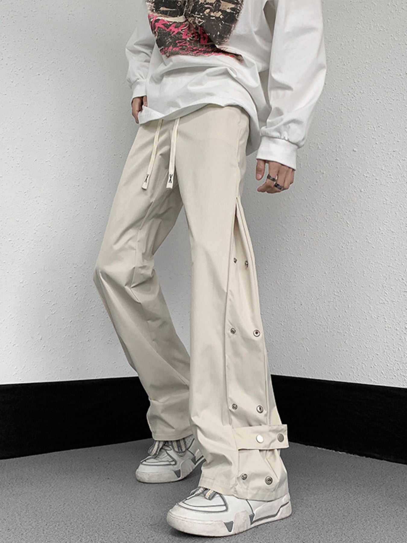 Men's beige sweatpants with snap button side detail and adjustable drawstring waist.