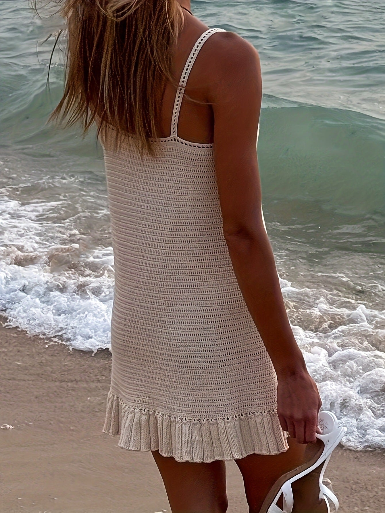Openwork crochet mini sweater dress in beige with ruffled hem and spaghetti straps.
