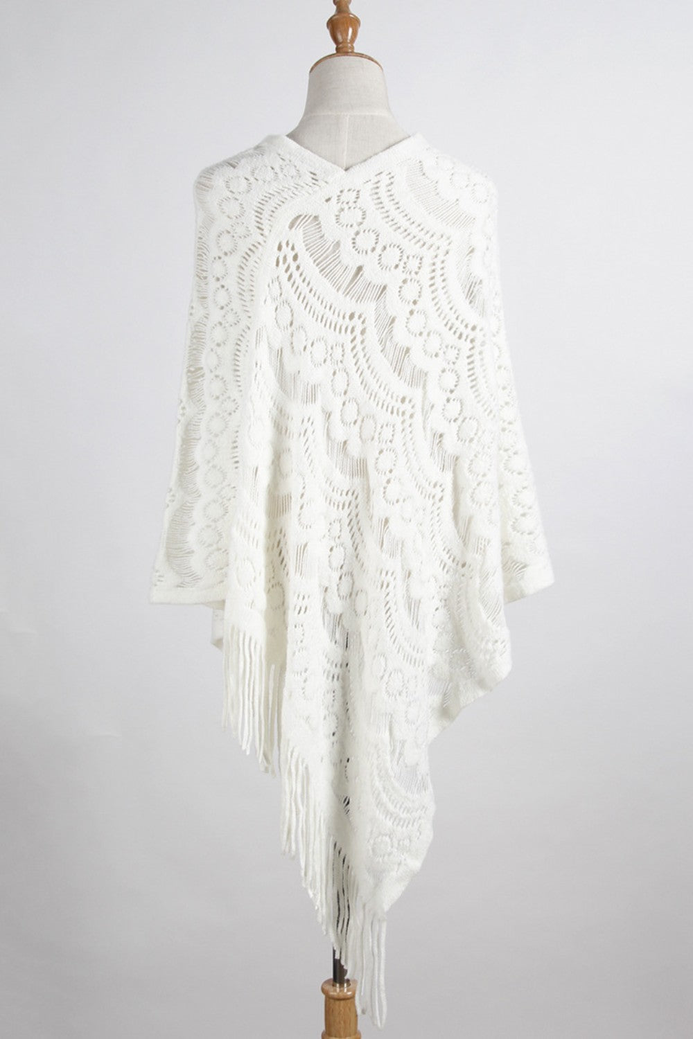 White crochet poncho with intricate pattern and fringe detail