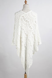 White crochet poncho with intricate pattern and fringe detail