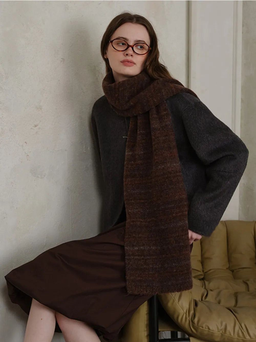 Textured mélange knit scarf in Chocolate, styled with a dark sweater and brown skirt.