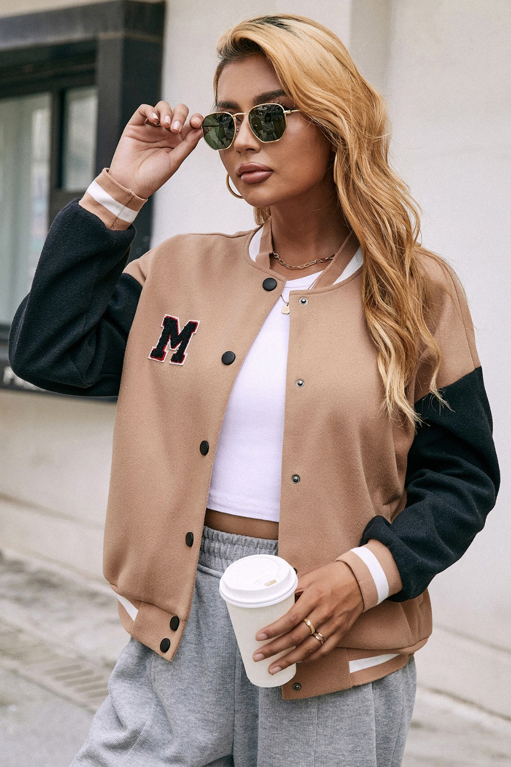 Camel bomber jacket with black sleeves, white striped cuffs, and an M patch.