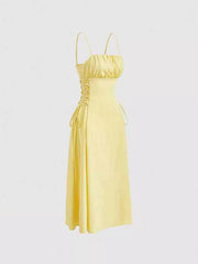 Light yellow cami dress with ruched bodice and crisscross lace-up sides.