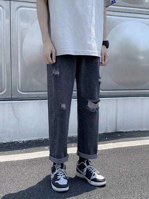 Distressed relaxed fit men's jeans in dark gray with cuffed hem and ripped details.