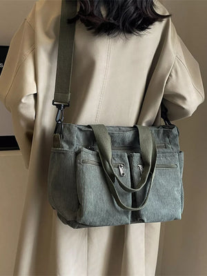 Green corduroy crossbody bag with multiple zippered pockets and adjustable strap.