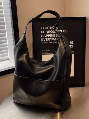 Black leather hobo shoulder bag with adjustable strap and front pocket detail.
