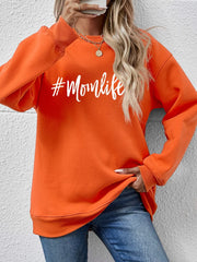 Crewneck sweatshirt in Pumpkin with white #Momlife graphic, long sleeves, and ribbed cuffs.