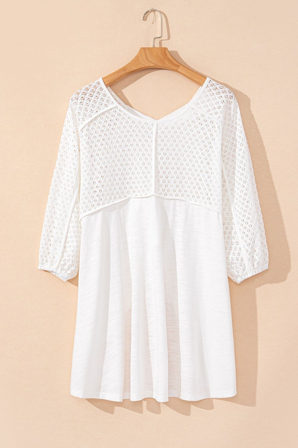 White lace-inset dolman sleeve blouse with a v-neck and textured fabric.