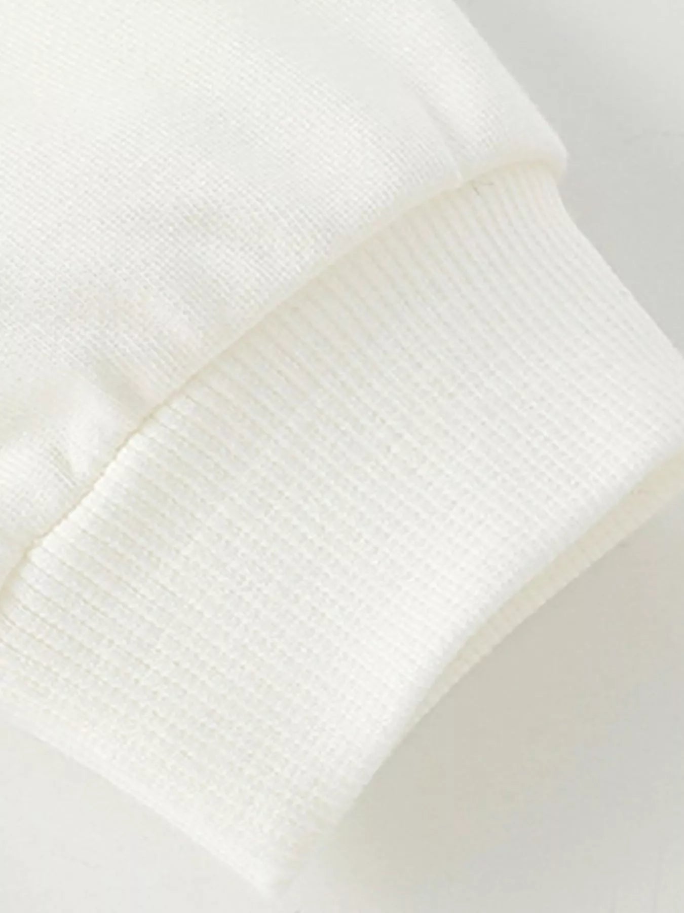 White kids' sweatshirt cuff detail with ribbed texture