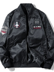 Black bomber jacket with embroidered patches including a jet and text.
