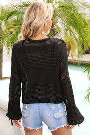 Black crochet crop sweater with tie-cuff detail and cable knit accents.