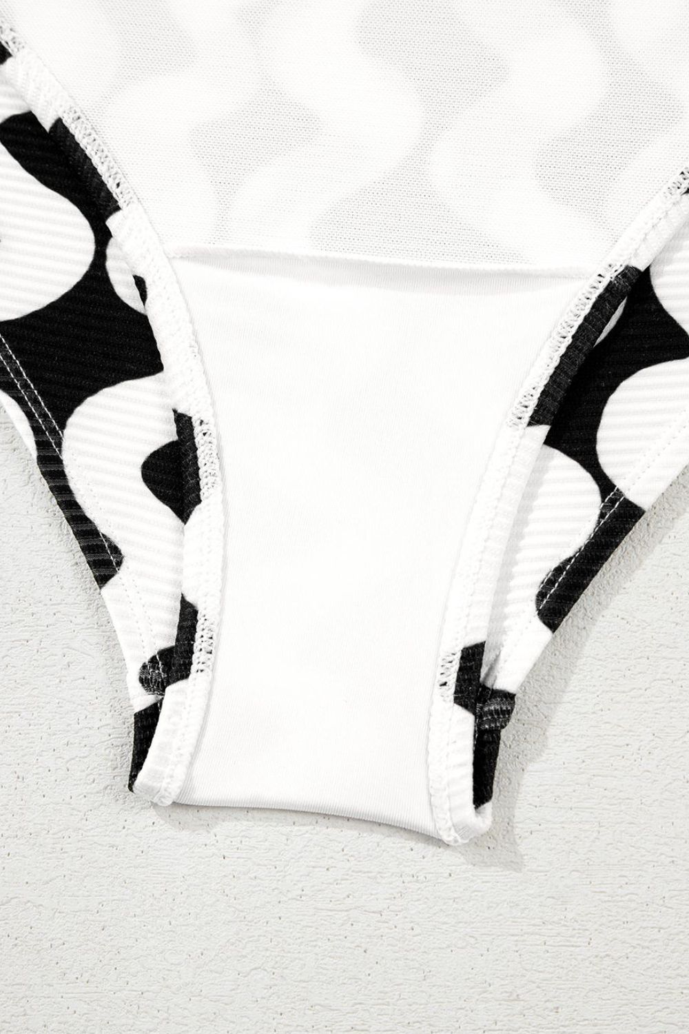 Black and white wave print one-piece swimsuit with a bow-front detail.