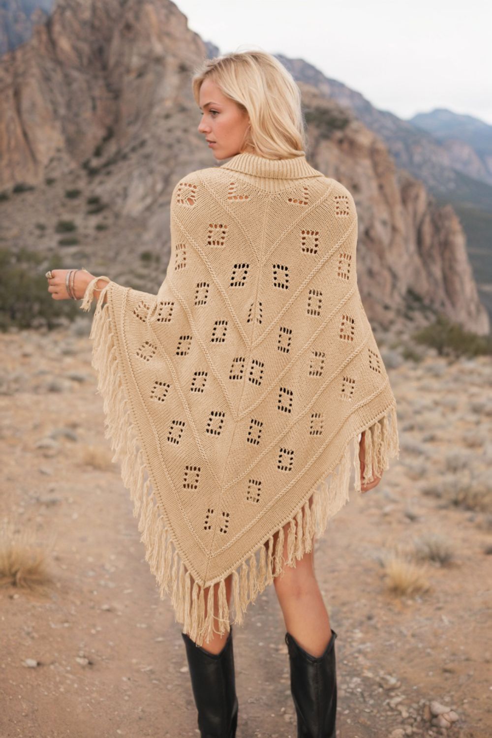 Tan knit poncho with geometric pattern and fringe, styled with black boots.