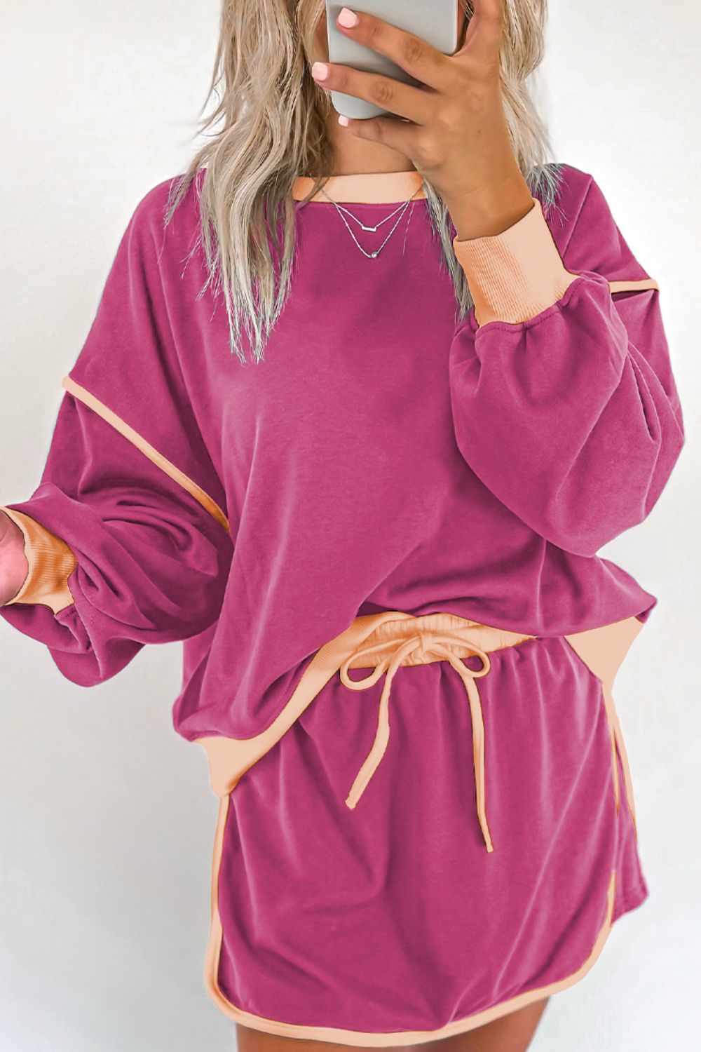 Contrast trim sweatshirt and skort set in red-violet with peach accents, drawstring waist, and balloon sleeves.
