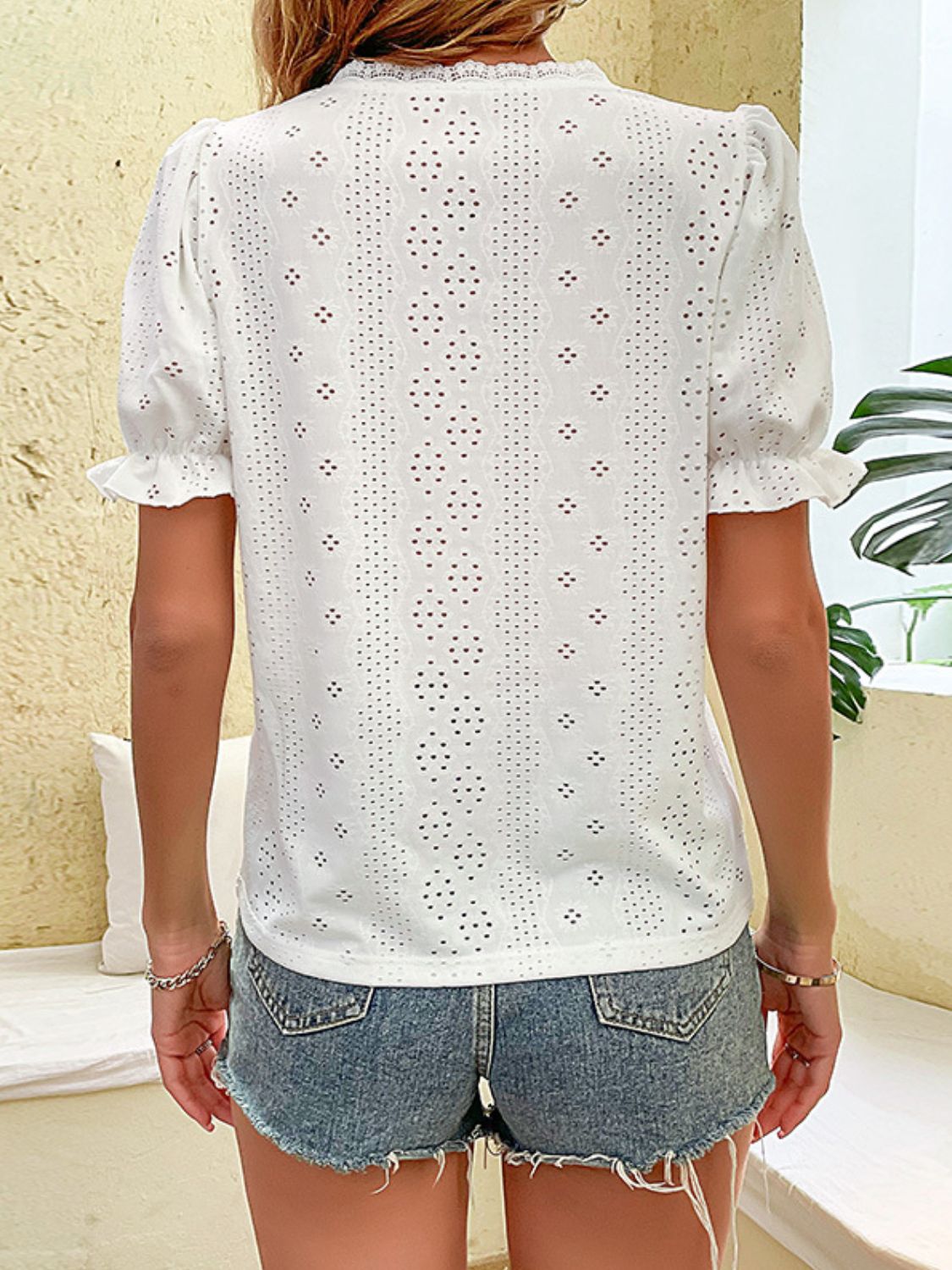 White eyelet embroidered puff sleeve blouse with ruffled cuffs.