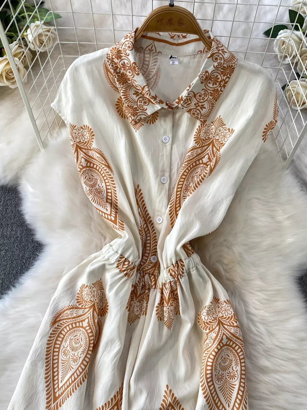 White button-down romper with brown paisley print, collared neckline, and elastic waist.