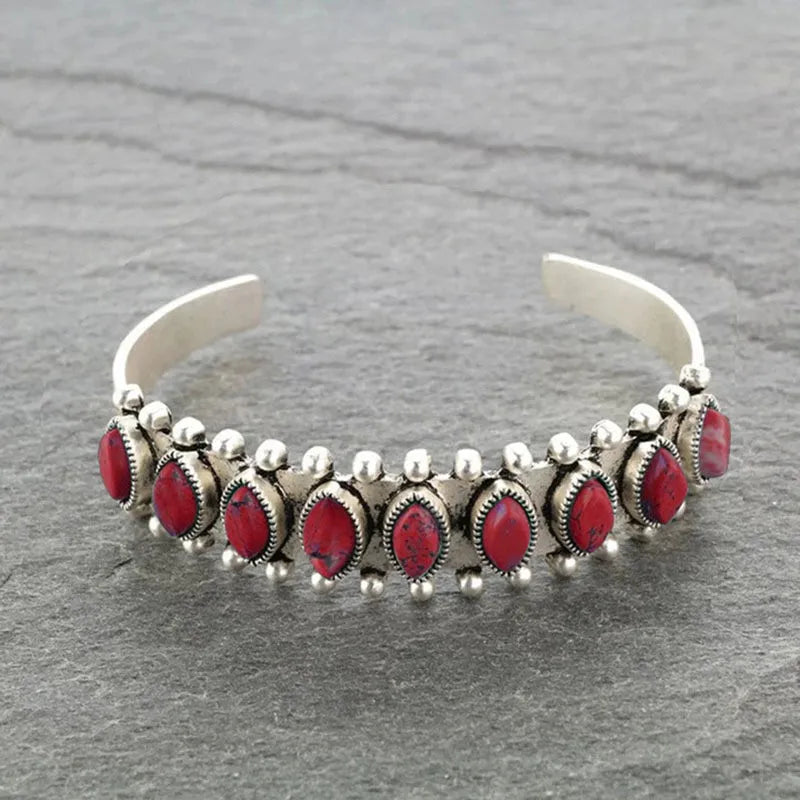 Silver open bangle bracelet with red cabochon stones and beaded details