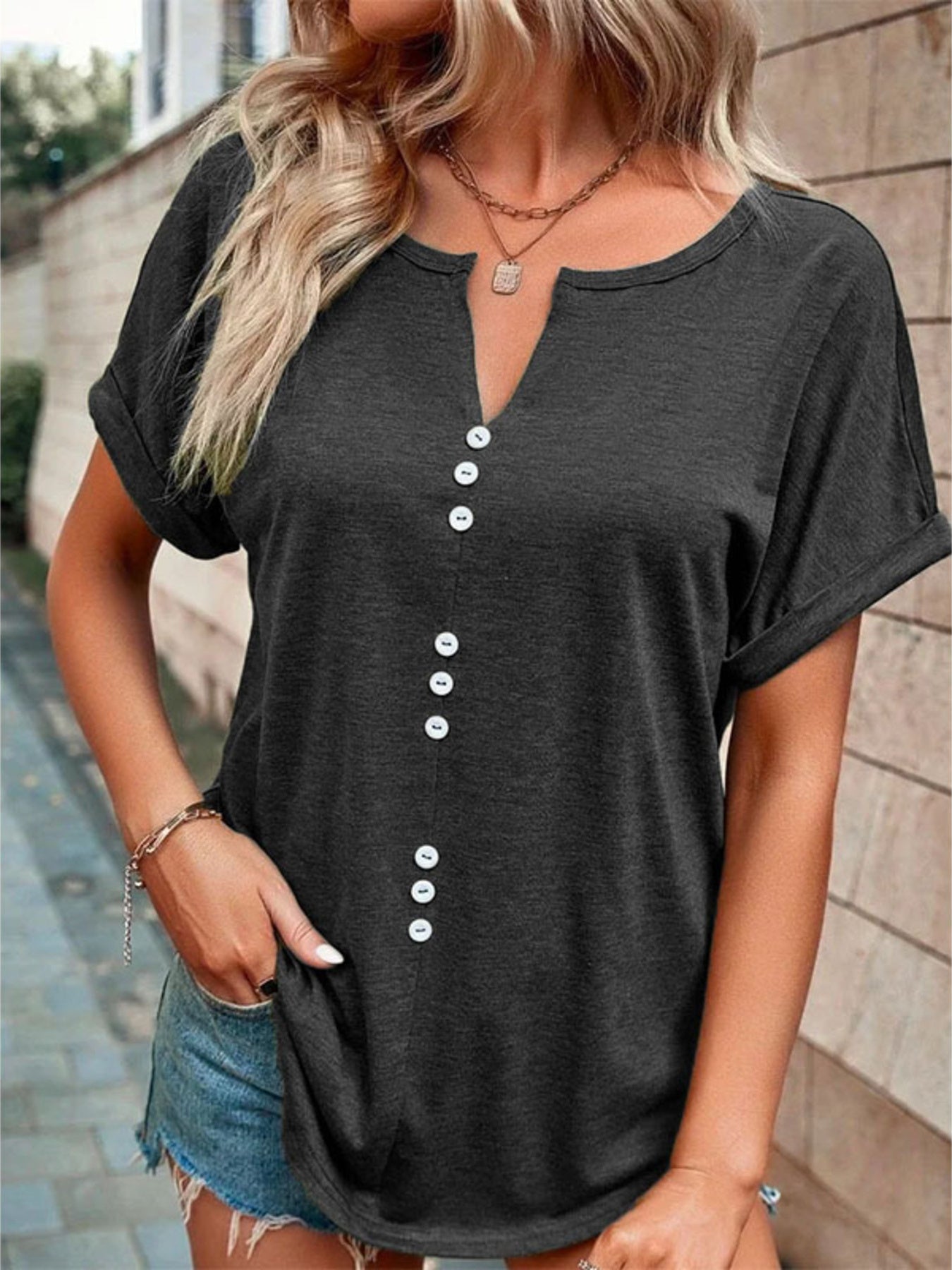 Buttoned V-neck short sleeve t-shirt in dark gray with decorative white buttons.