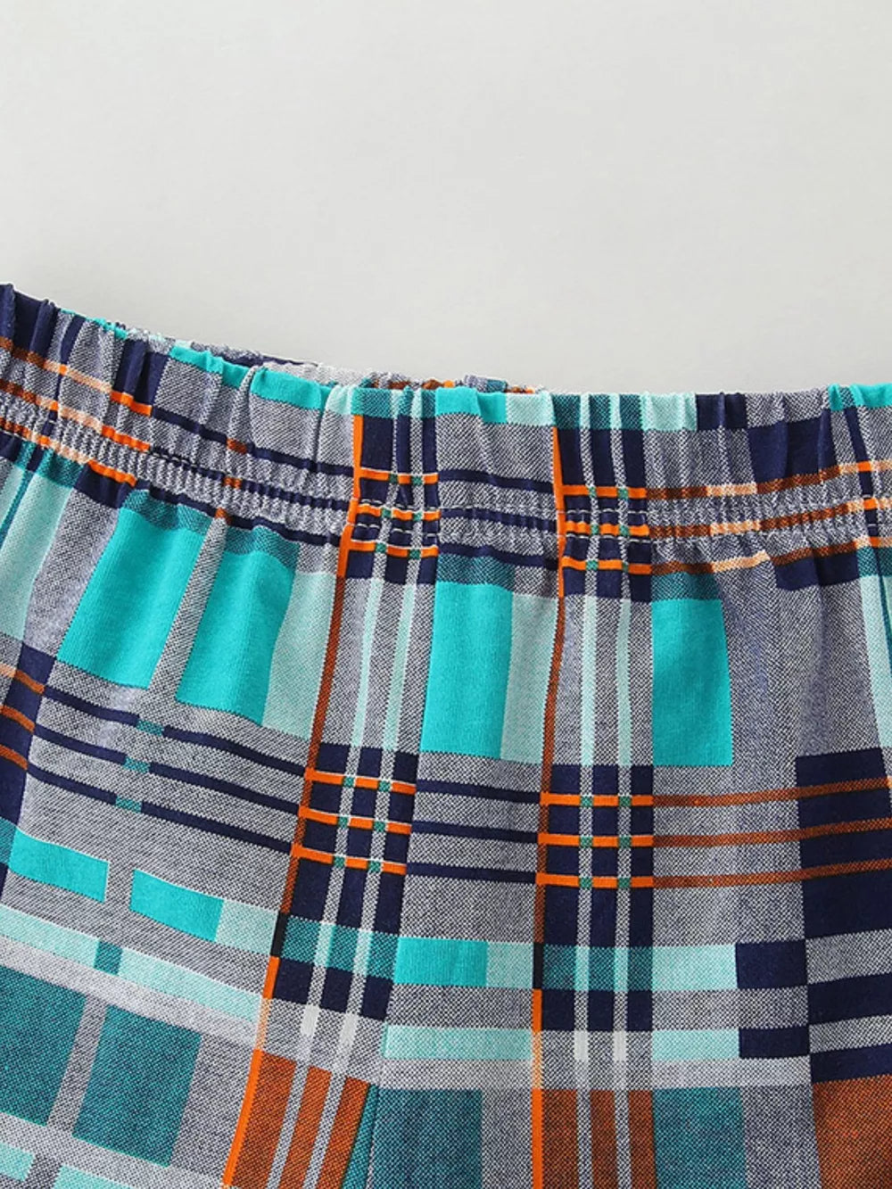 Toddler shorts with elastic waistband and blue, teal, orange plaid pattern.