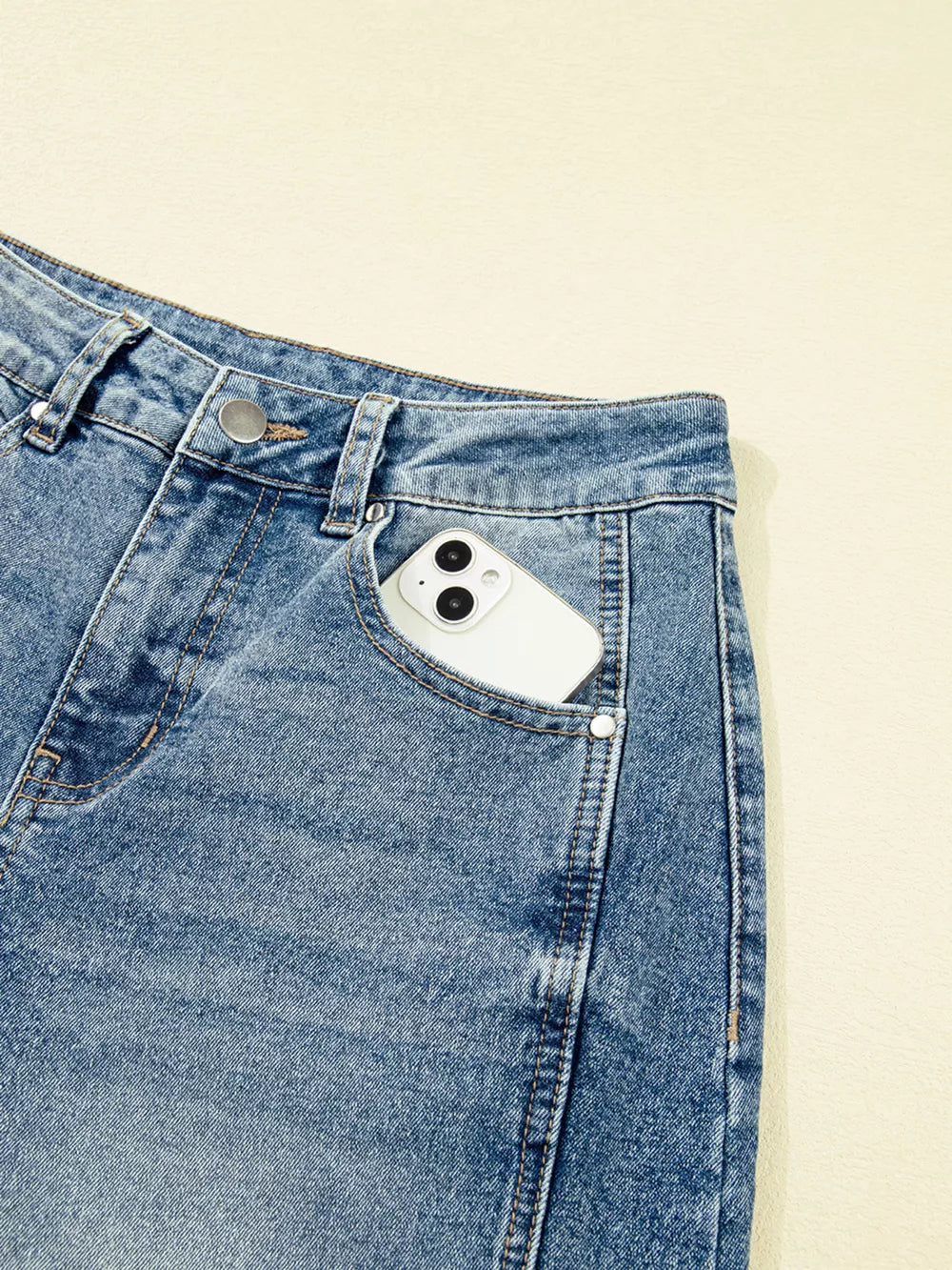 Vintage-inspired high-waisted seam jeans in light wash denim with a phone in the pocket.