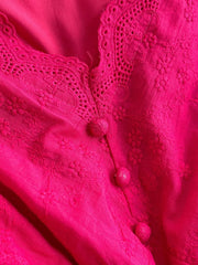Pink lace-embellished midi dress with floral embroidery and button details.
