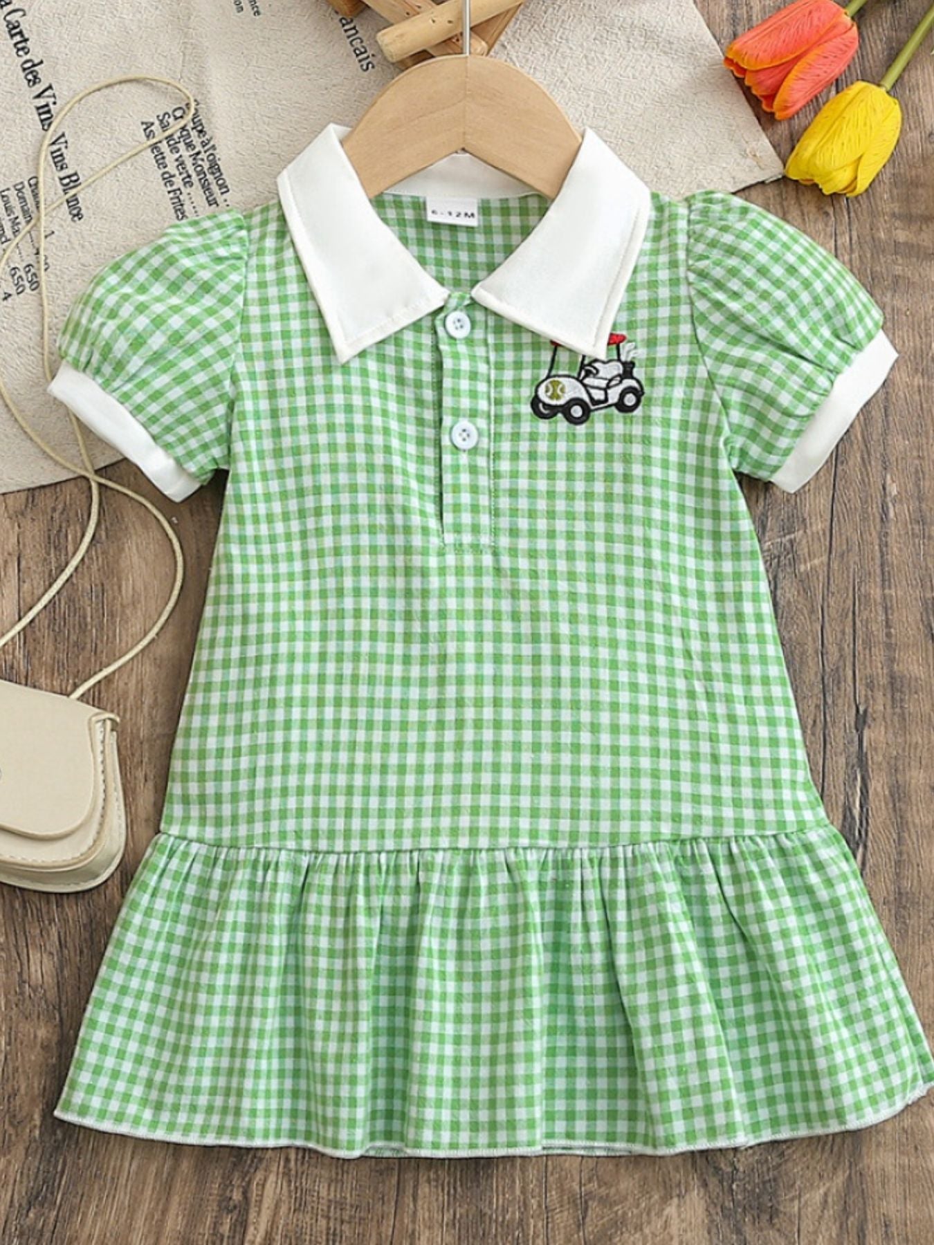 Baby green gingham polo dress with white collar, short sleeves, and ruffle hem.