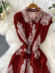 Wine red collared button-down romper with white paisley print and short sleeves.