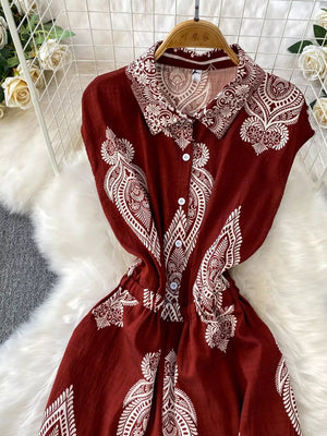 Wine red collared button-down romper with white paisley print and short sleeves.
