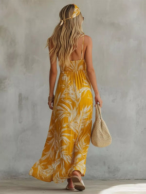 Yellow spaghetti strap maxi dress with tropical leaf print, smocked bodice, and flowing skirt.