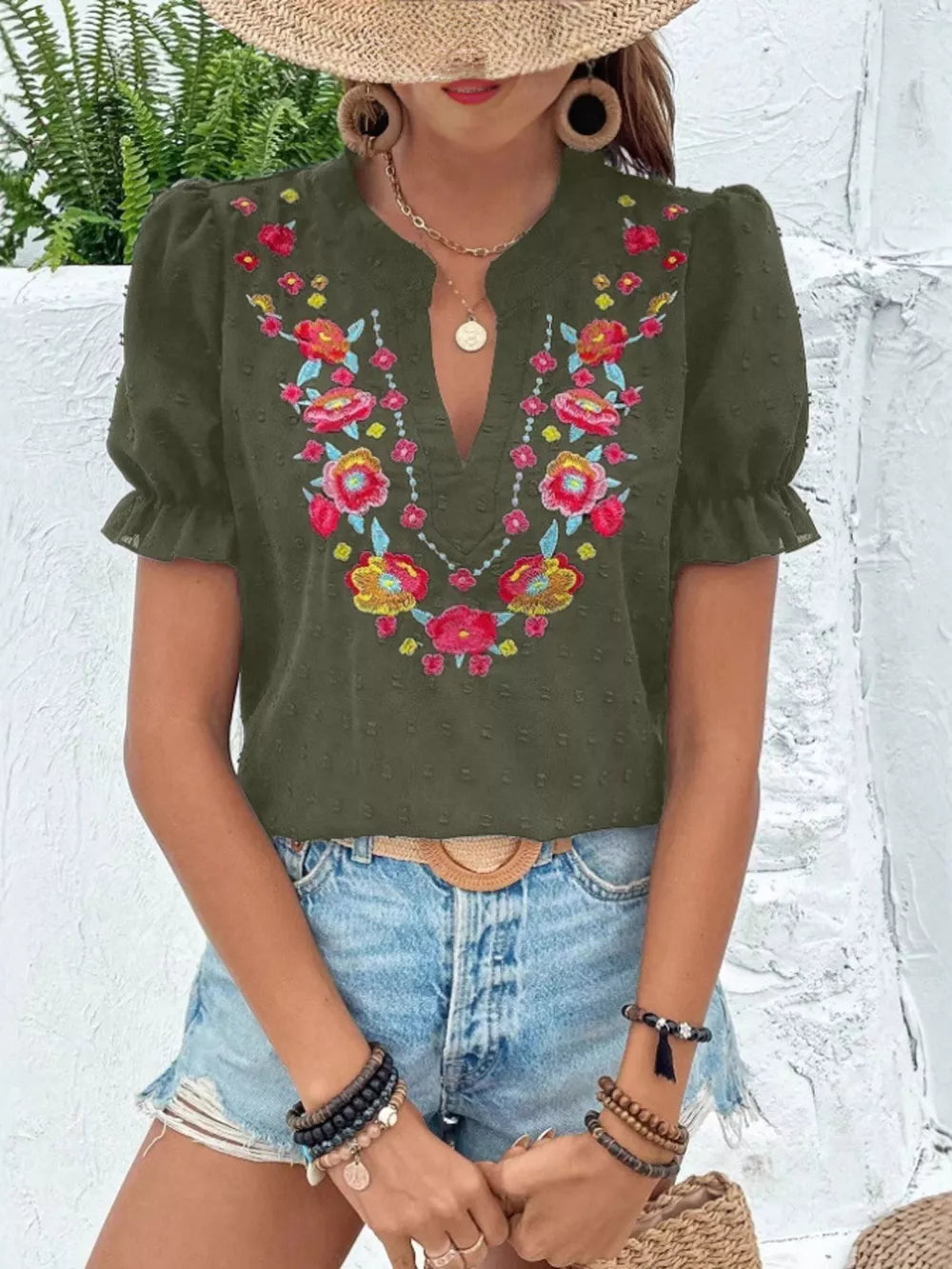 Army green blouse with floral embroidery, puff sleeves, and a notched neckline.