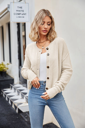 Cream textured knit cropped cardigan with buttons and round neckline.