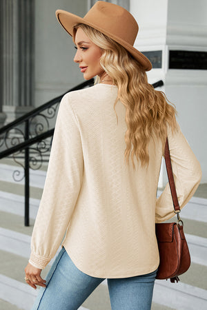 Cream textured V-neck blouse with lace trim cuffs and long sleeves.