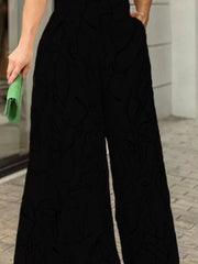 Black halter neck romper with abstract line print and wide legs.