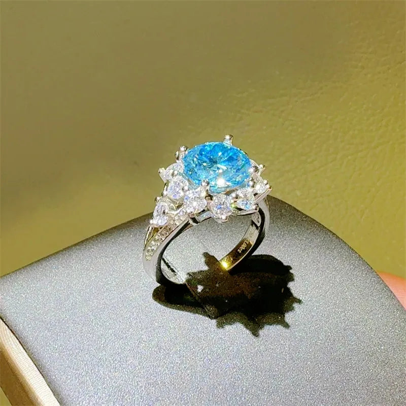 Sterling silver ring with a bright blue oval center stone surrounded by clear accent stones.