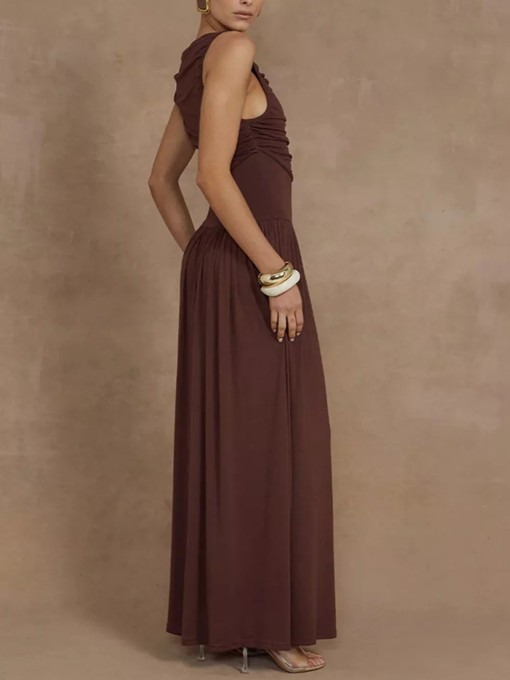 Brown ruched maxi dress with asymmetric neckline and sleeveless cut.