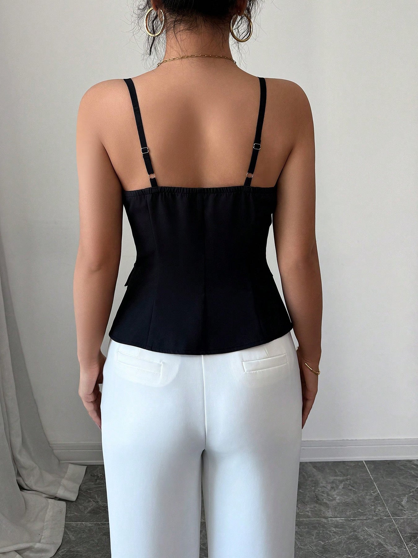 Black V-cut cami top with adjustable spaghetti straps and button front detail.