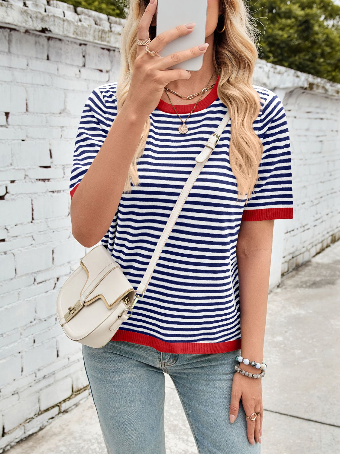 Striped knit tee with red trim and short sleeves, styled with a crossbody bag.