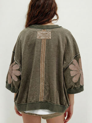 Mineral wash green cotton sweatshirt with flower patches on sleeves and back detail.