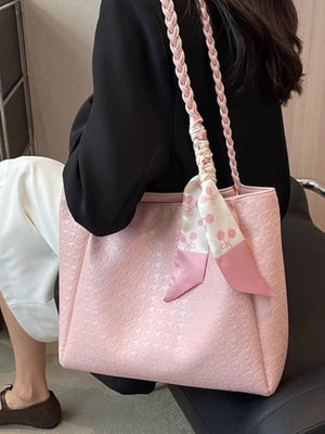 Pink shopper bag with braided handles and cherry print scarf detail.