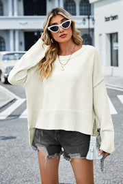 Cream acrylic sweater with flared sleeves and side slits, styled with denim shorts.
