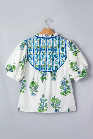 White polyester shirt with blue floral print, puff sleeves, and ruffled neckline.