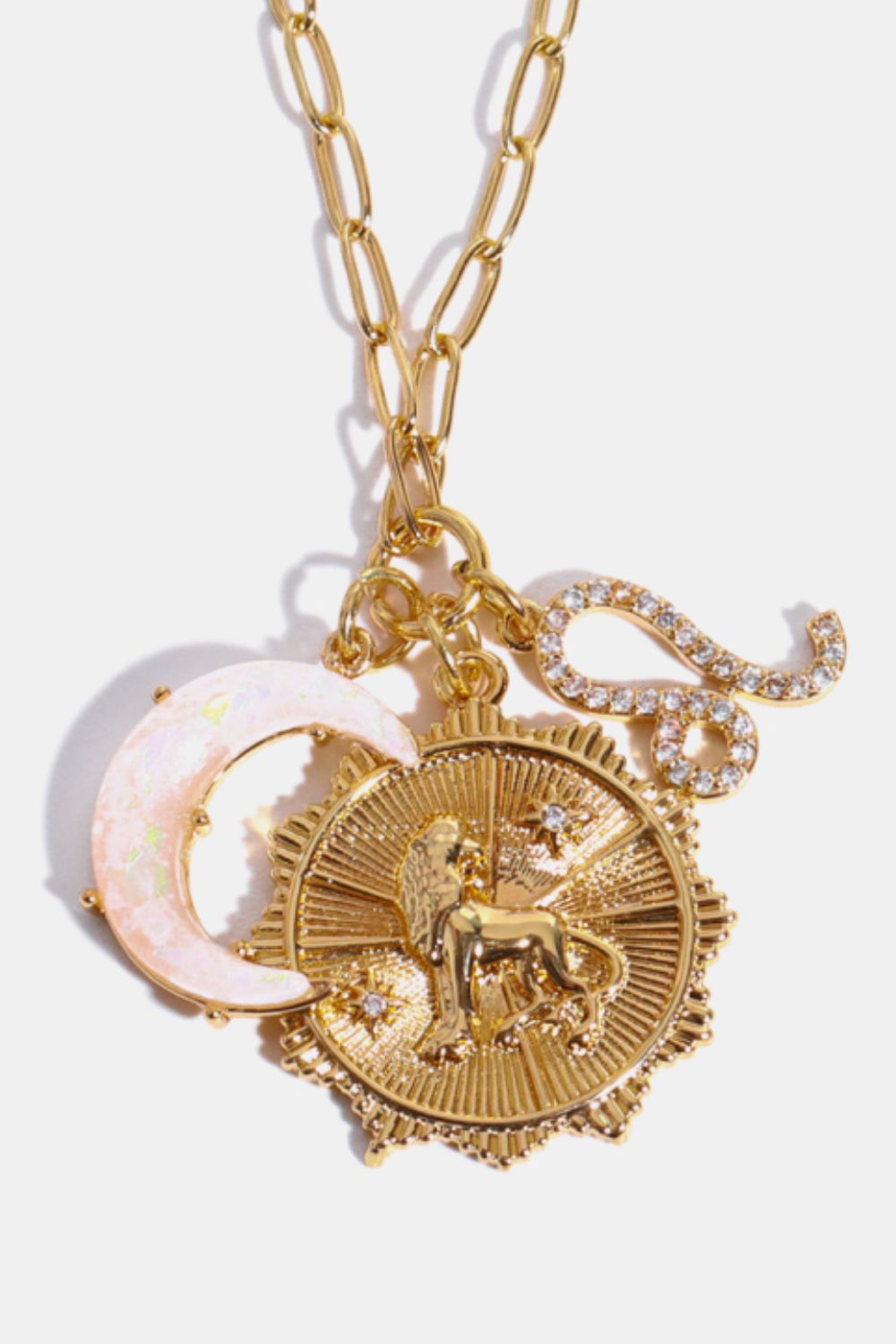 Gold pendant necklace with Leo zodiac, moon, and S-shaped charm.