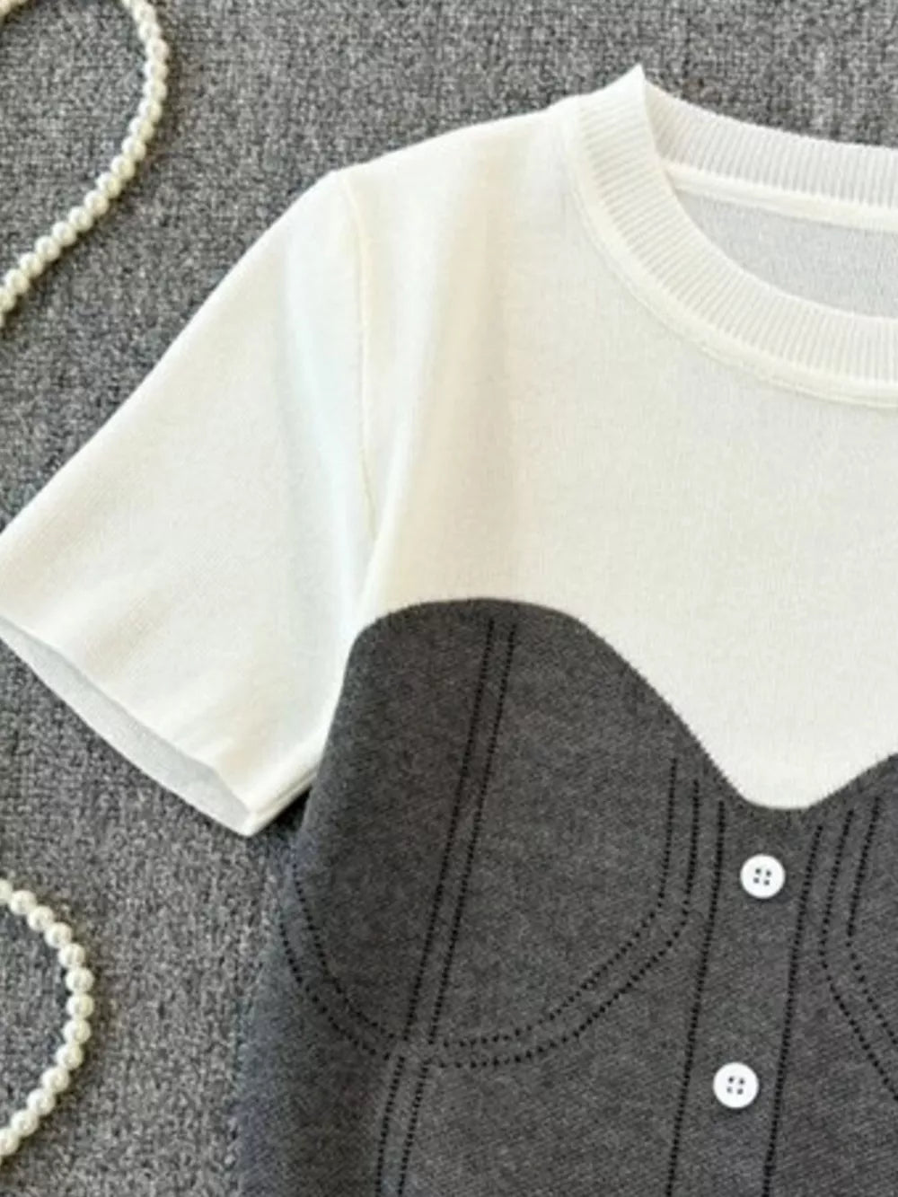 Color block knit t-shirt in white and gray with ribbed detail and button accents.