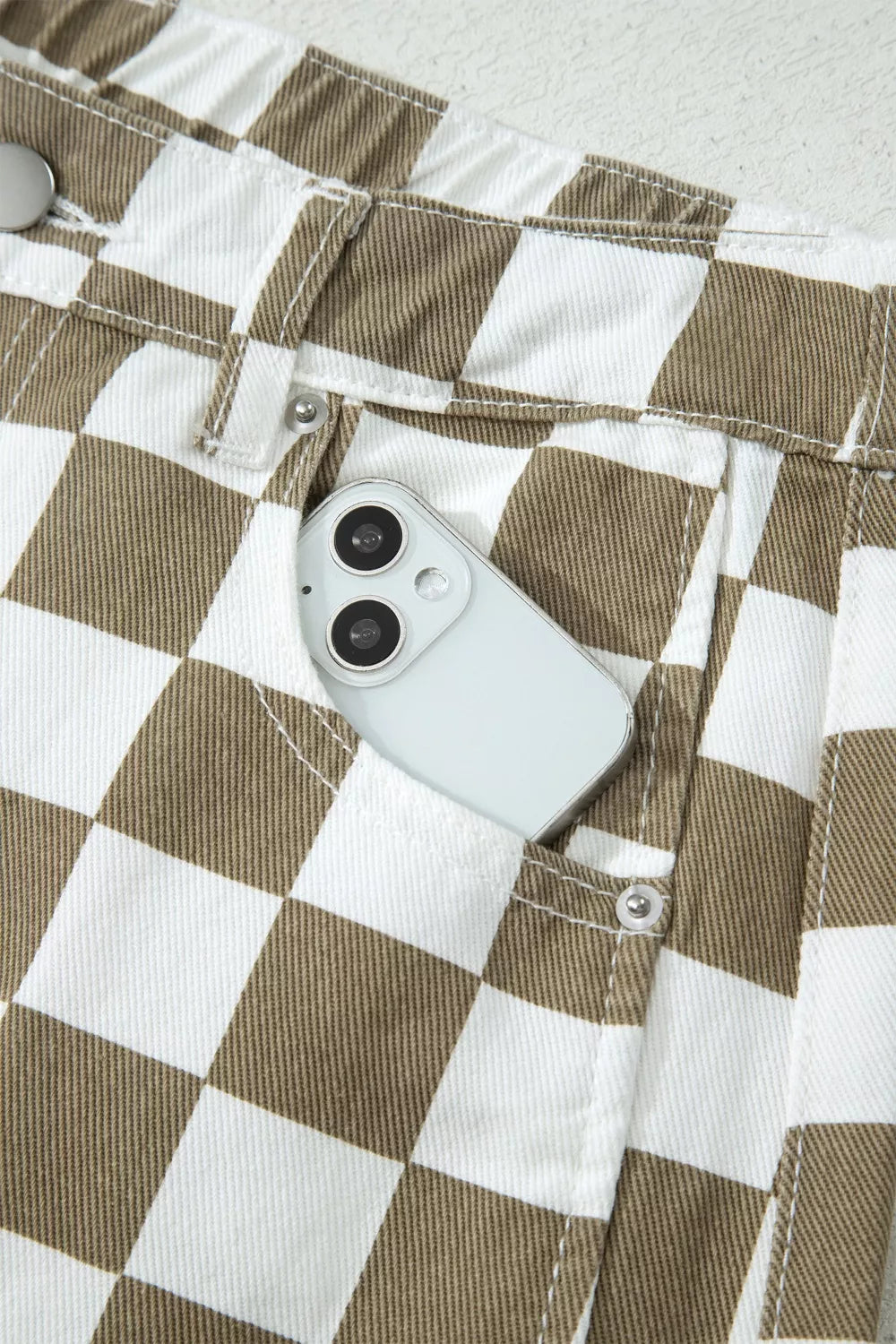 Chic checkered denim barrel pants in brown and white with a phone in the pocket.