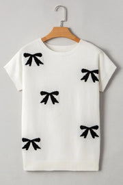 White knit tunic with black bow motif pattern, short sleeves, and crew neck.