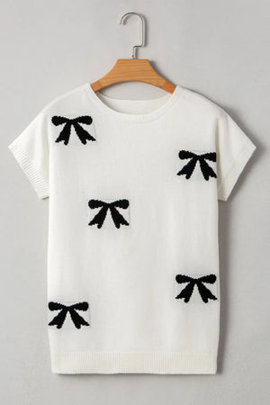 White knit tunic with black bow motif pattern, short sleeves, and crew neck.